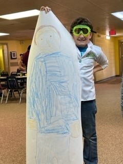 Boy wearing goggles holding up a drawing
