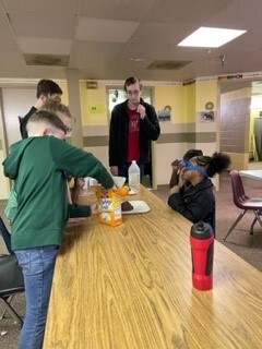 Students gathered around a table eating snacks