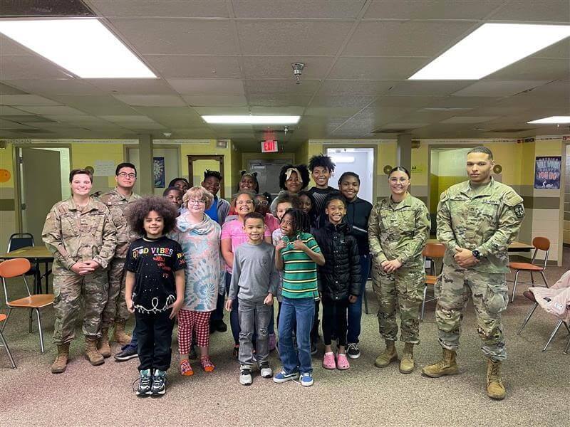 Smiling students posing with 4 military members