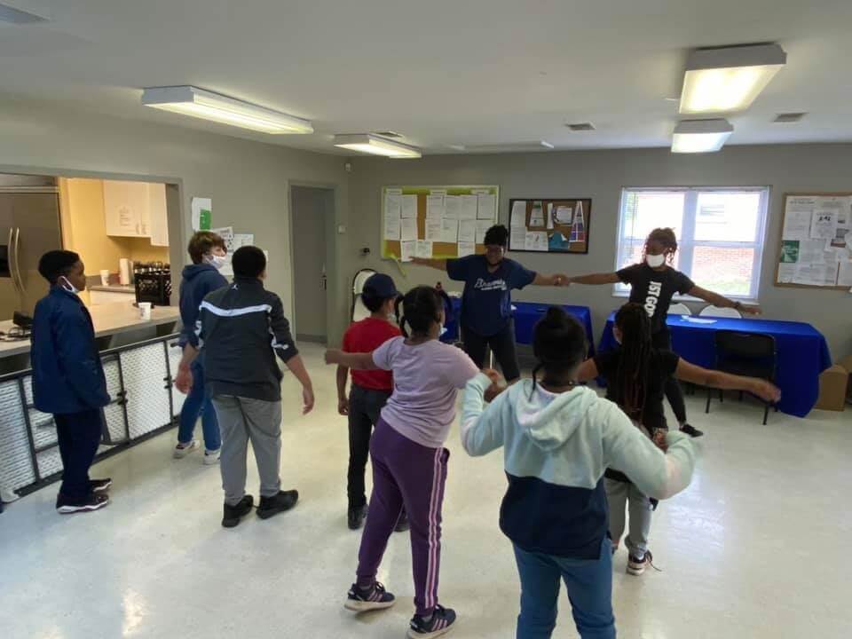 2 teachers demonstrating stretching for a group of students