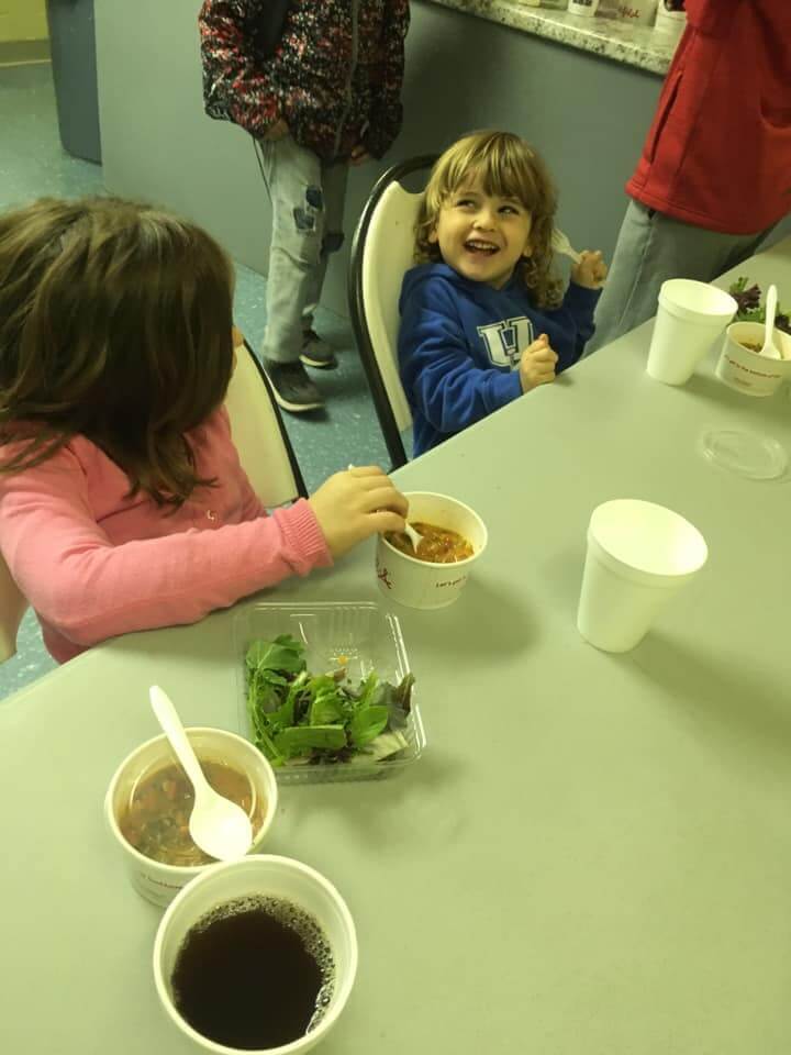 2 children eating soup and salad and laughing