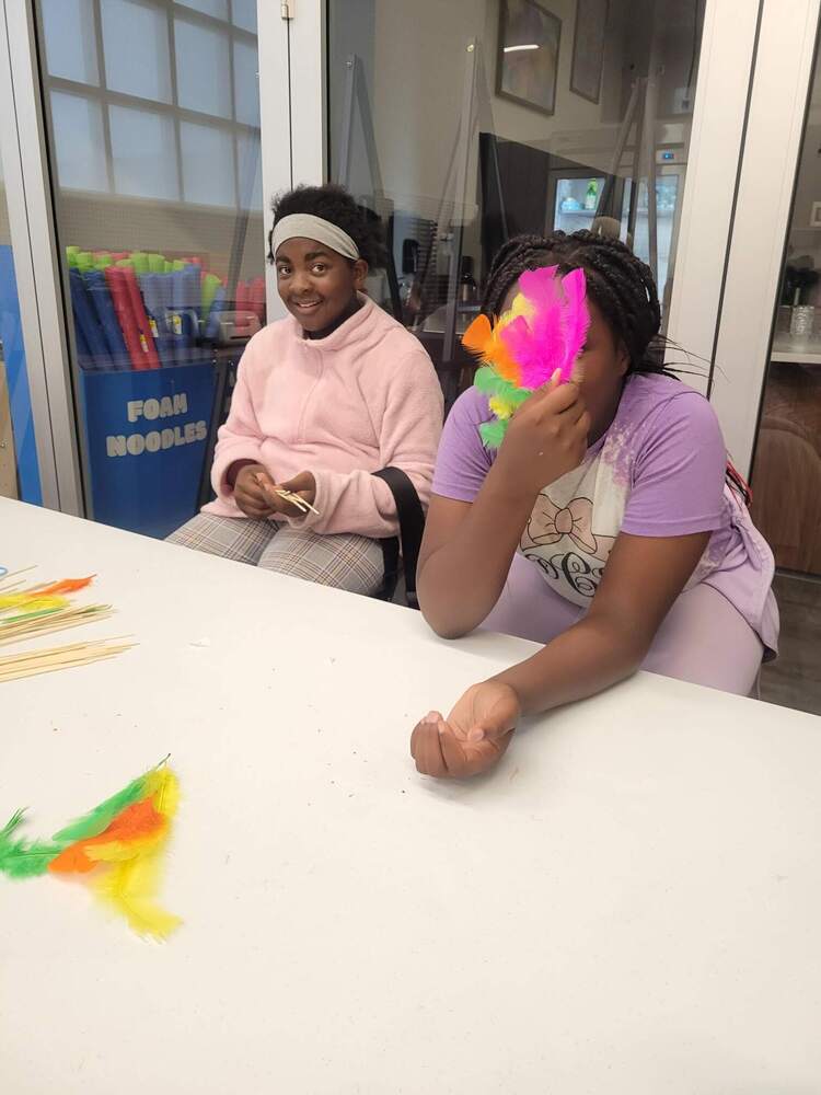 two girls making crafts and playing with feathers