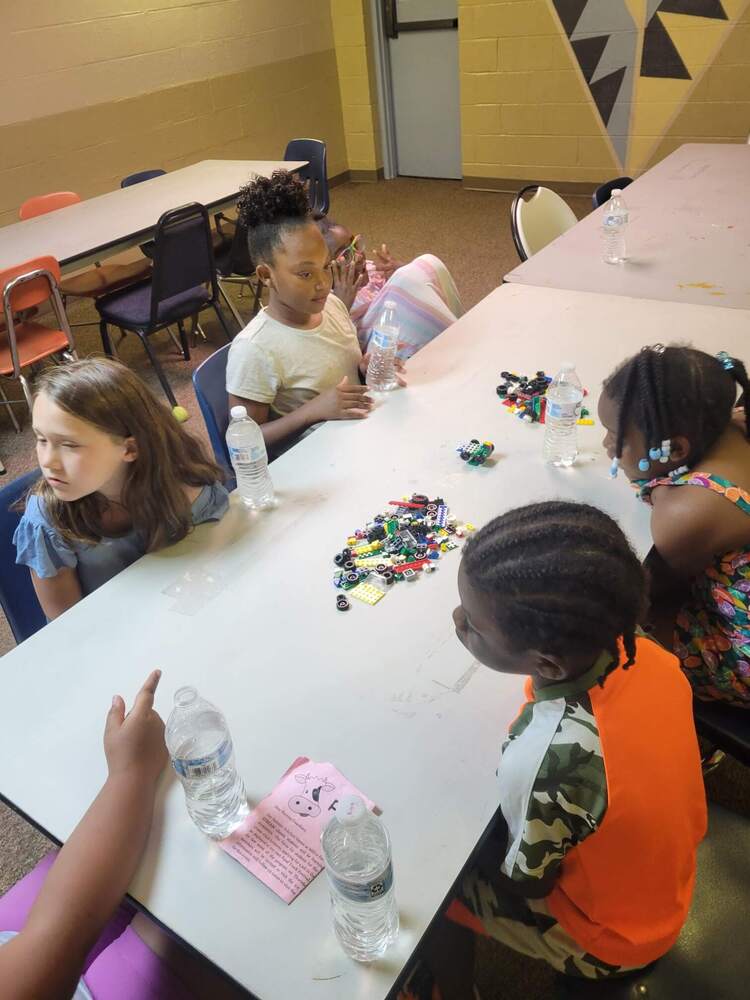 A group of children sitting at a table playing with label