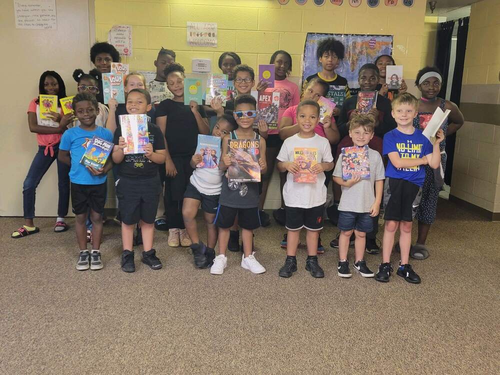 A group of kids holding up their books.