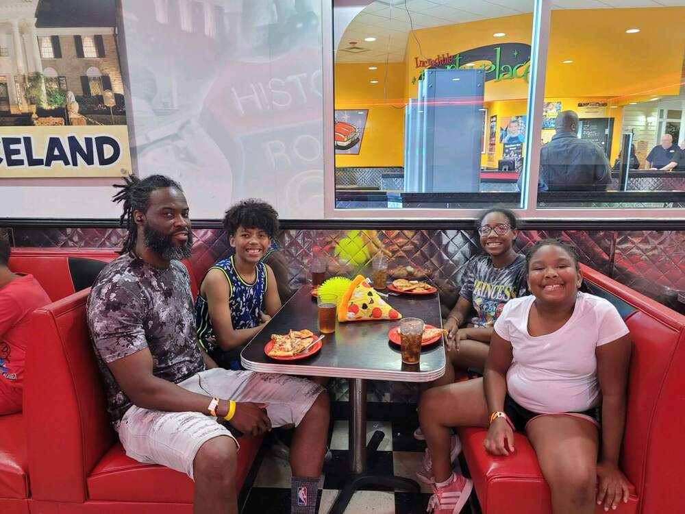 A family sitting at a booth in a restaurant eating pizza.