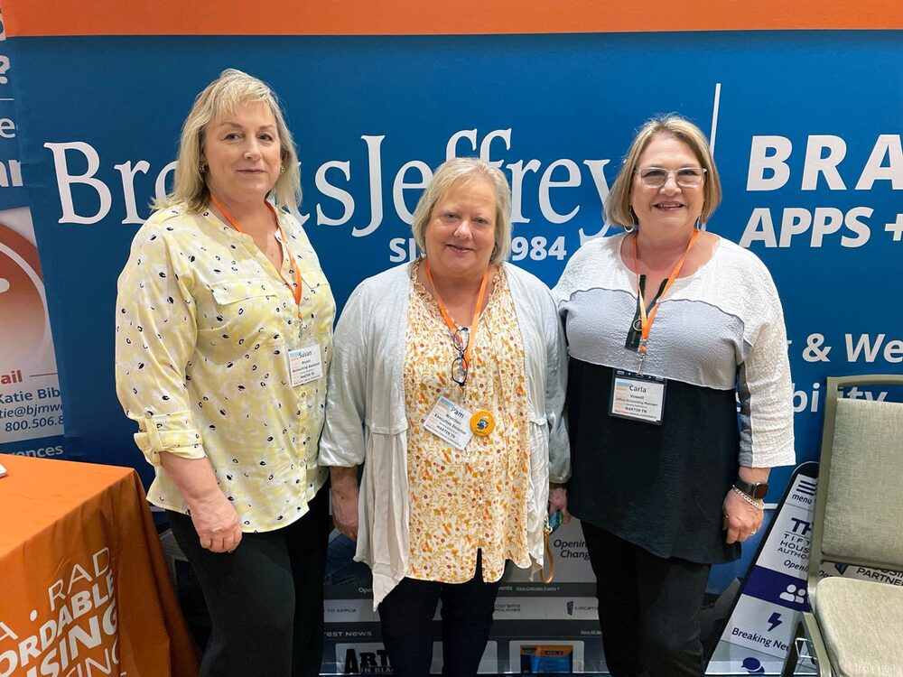 Susan Bryant, Accounting Assistant; Pam Bratcher, ED; Carla Vowell, Office and Accounting Manager (Martin, TN) are standing in front of their booth space at the TAHRA Conference.