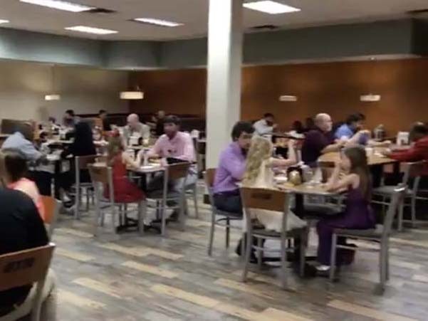 Dads and daughters are all seated together at tables, happily eating their food.