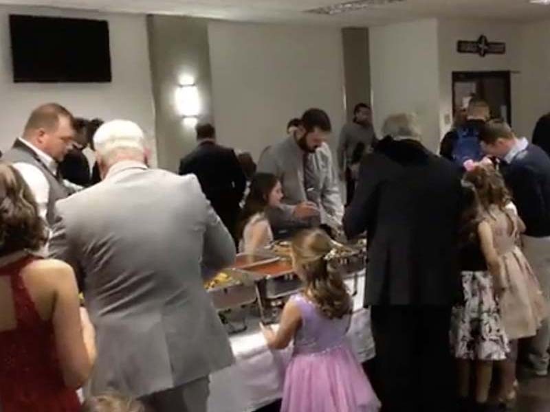 Dads are lined up at buffet tables with their daughters. 