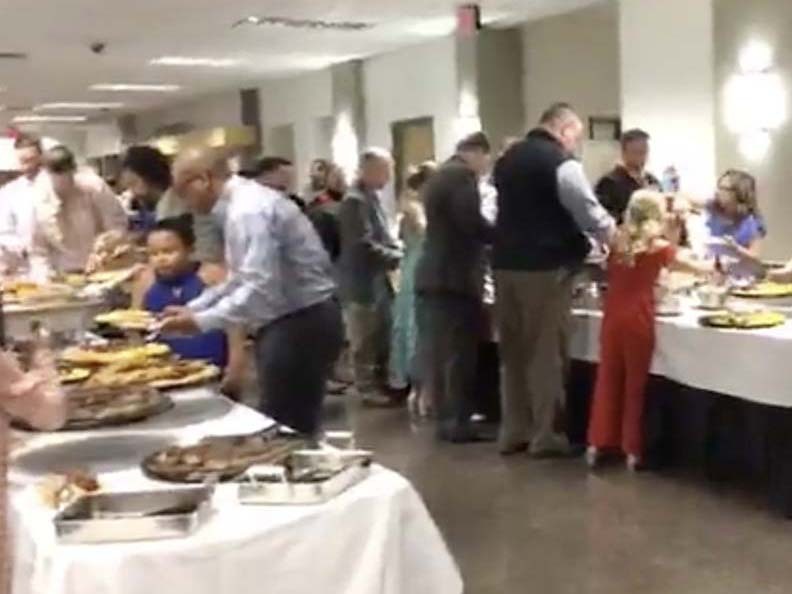 Dads are lined up at buffet tables with their daughters, helping them pile their plates full of food.