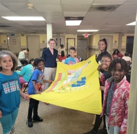 A group of kids and teachers holding up a periodic table that they made.