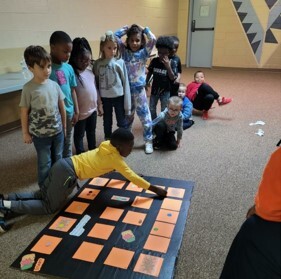 A group of kids standing in a line playing a game with cards.